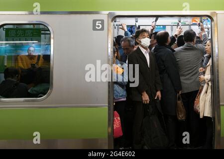 Un homme portant un masque sur un train bondé à Tokyo, au Japon Banque D'Images