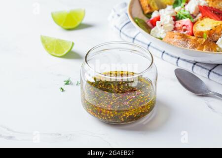 Vinaigrette à la moutarde, à l'huile d'olive et à l'aneth dans un pot en verre. Cuisine saine concept. Banque D'Images