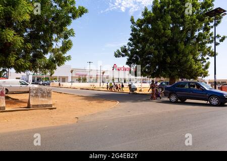 MBOUR, SÉNÉGAL - VERS DÉCEMBRE 2020. Vue sur le logo du supermarché Auchan et le parking depuis la route principale. Auchan est une chaîne de supermarchés internationale française, Banque D'Images