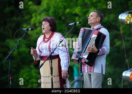 Femme d'âge Mddle en costumes de broderie traditionnels ukrainiens chantant sur scène, accordéoniste jouant pendant le concert consacré à la Journée du village. Juin Banque D'Images