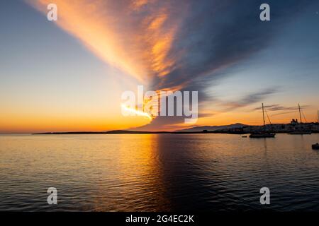 Magnifique lever de soleil avec une rangée de nuages orange et violet saturés dans le ciel vu depuis le bateau en début de matinée à Naoussa Village, Grèce. Banque D'Images