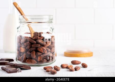 Fèves de cacao dans un pot en verre sur une table de cuisine légère. Cuisine alimentaire expérience culinaire pour la fabrication du chocolat traditionnel. Mise au point sélective Banque D'Images