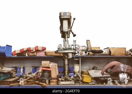 Ancien banc d'atelier désordonné avec perceuse à pression et outils isolés sur fond blanc Banque D'Images