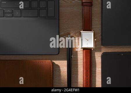 Vue depuis le dessus de la table de bureau avec ordinateur portable, ordinateur portable, stylo et montre de poignet Banque D'Images