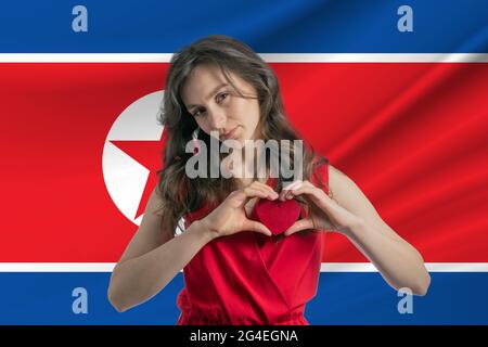Amour de la Corée du Nord UNE fille tient un coeur sur sa poitrine dans ses mains contre le fond du drapeau de la Corée du Nord Banque D'Images