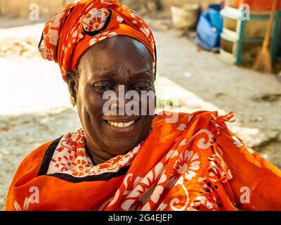 MBOUR, SÉNÉGAL - JANVIER CIRCA, 2021. sénégalaise non identifiée jolie femme mûre en robe traditionnelle en plein air regardant sourire. Pauvreté et bonheur Banque D'Images
