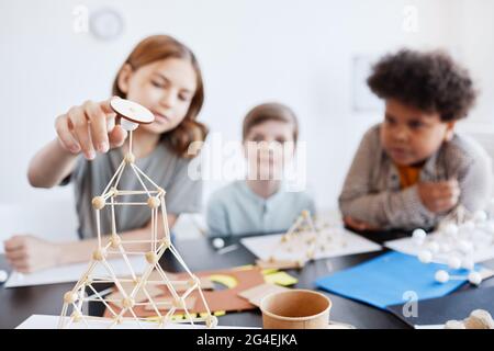 Portrait d'une jeune fille qui fait des modèles en bois pendant la classe d'art et d'artisanat à l'école, se concentre sur le premier plan, espace de copie Banque D'Images