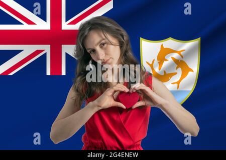 J'adore Anguilla. Une fille tient un coeur sur sa poitrine dans ses mains contre le fond du drapeau d'Anguilla. Le concept de patriotisme. Banque D'Images