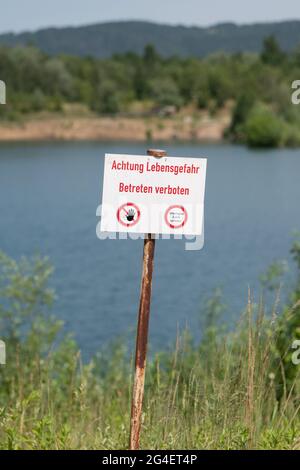 Pirna, Allemagne. 21 juin 2021. Un panneau portant l'inscription « attention - danger de mort - ne pas entrer » se trouve devant une fosse de gravier. En raison de plusieurs accidents mortels de natation ces derniers jours dans les rivières et les lacs, la Société allemande de sauvetage (DLRG) met en garde contre les risques de nager dans ces eaux. Credit: Sebastian Kahnert/dpa-Zentralbild/dpa/Alay Live News Banque D'Images