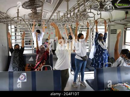 Mumbai, Inde. 21 juin 2021. Les femmes portant des masques faciaux comme mesure de précaution contre la propagation de covid-19 pratiquer l'exercice de yoga à l'intérieur d'un train local à Mumbai.la Journée internationale de yoga est célébrée dans le monde entier le 21 juin chaque année. (Photo par Ashish Vaishnav/SOPA Images/Sipa USA) crédit: SIPA USA/Alay Live News Banque D'Images