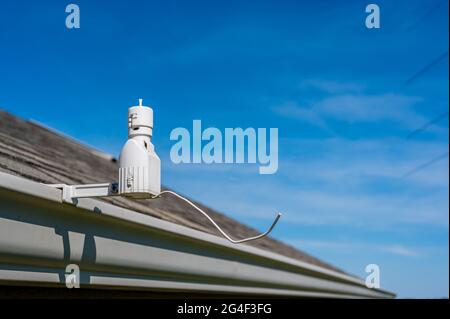 Détecteur de pluie sprinkleur sans fil utilisé pour économiser l'eau. Le dispositif est installé sur une gouttière de toit résidentielle Banque D'Images