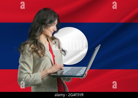 Freelance au Laos belle jeune femme freelance utilise ordinateur portable sur le fond du drapeau du Laos. Banque D'Images