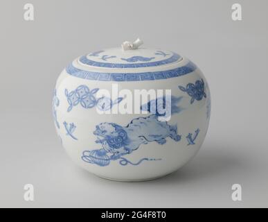 Pot rond couvert avec des symboles shishi et de bon augure. Récipient rond en porcelaine, peint en bleu sous-brillant. Sur le mur extérieur quatre fois un shishi (chien lion) avec des symboles de bonheur (cornes, pièces) entre les deux. Sur l'épaule une bande avec un motif méandre. Le couvercle avec la même décoration; bouton sous la forme d'une branche de bambou. Hirado bleu-blanc. Banque D'Images