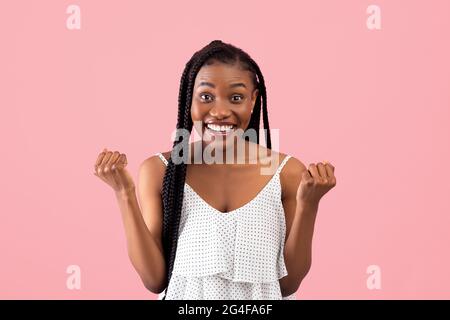 Femme noire excitée en robe d'été gestante OUI sur fond rose studio Banque D'Images