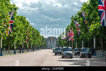 Taxis londoniens dans la rue The Mall avec des drapeaux de Grande-Bretagne alignés, à l'arrière Buckingham Palace, City of Westminster, Londres, Angleterre, Great Banque D'Images