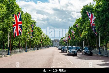 Taxis londoniens dans la rue The Mall avec des drapeaux de Grande-Bretagne alignés, à l'arrière Buckingham Palace, City of Westminster, Londres, Angleterre, Great Banque D'Images