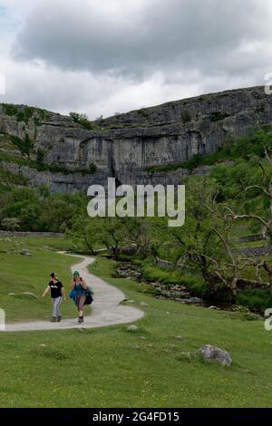 Une paire de randonneurs heureux font leur dos le long du chemin depuis le joyau pittoresque de Malham Cove dans le parc national de Yorkshire Dales Banque D'Images