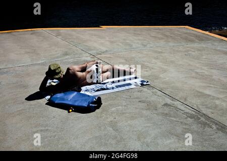 Un homme se prélassant au soleil sur la plage de Clovelly. Clovelly, près de Bondi, est l'une des plages de l'est de Sydney. Banque D'Images