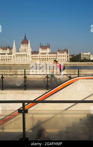 La station de métro Batthyany Ter escalier, cycliste, Danube et le Parlement national hongrois Assemby en arrière-plan, Budapest, Hongrie Banque D'Images