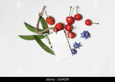 Étiquette cadeau vierge, étiquette de prix isolée sur fond blanc de table au soleil. Image de marque. Concept de vente d'été. Cerises fruits Banque D'Images