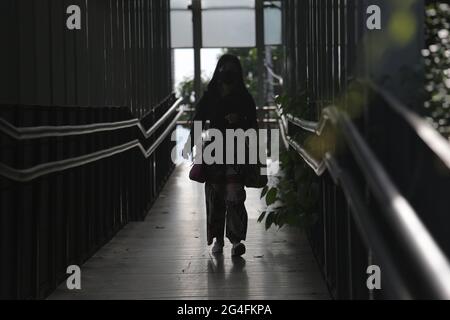 Au milieu de la menace d'une augmentation des cas de Covid-19 dans la région de la capitale spéciale de Jakarta, un travailleur portant un masque se rend à son bureau dans la zone du bureau de rue Thamrin, dans le centre de Jakarta, en Indonésie, le lundi 21 juin, 2021. Les décès dus à Covid-19 à Jakarta ont de nouveau augmenté. Il est demandé aux habitants de la région de la capitale spéciale de Jakarta de continuer à faire preuve de vigilance face au taux d'ajout des cas Covid-19. Aujourd'hui, le nombre total de cas en Indonésie a atteint 2 millions de cas, la région de la capitale spéciale de Jakarta, qui est toujours le centre de la propagation du virus. (Photo Banque D'Images