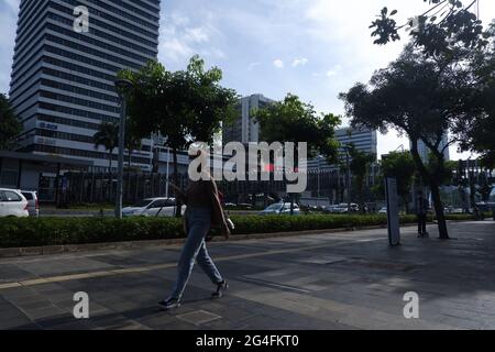 Au milieu de la menace d'une augmentation des cas de Covid-19 dans la région de la capitale spéciale de Jakarta, un travailleur portant un masque se rend à son bureau dans la zone du bureau de rue Thamrin, dans le centre de Jakarta, en Indonésie, le lundi 21 juin, 2021. Les décès dus à Covid-19 à Jakarta ont de nouveau augmenté. Il est demandé aux habitants de la région de la capitale spéciale de Jakarta de continuer à faire preuve de vigilance face au taux d'ajout des cas Covid-19. Aujourd'hui, le nombre total de cas en Indonésie a atteint 2 millions de cas, la région de la capitale spéciale de Jakarta, qui est toujours le centre de la propagation du virus. (Photo Banque D'Images