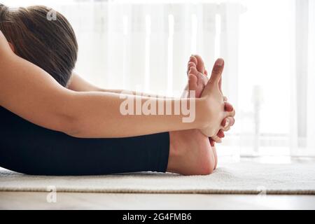 Vue rognée de la jeune femme pratiquant le yoga, assis dans l'exercice assis de virage vers l'avant, Paschimottanasana pose Banque D'Images