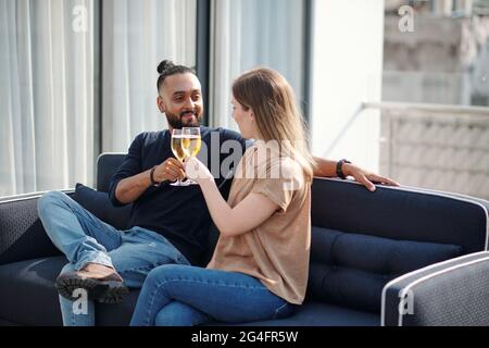 Joyeux homme barbu élégant buvant du champagne avec jeune femme jolie à la fête sur le toit Banque D'Images