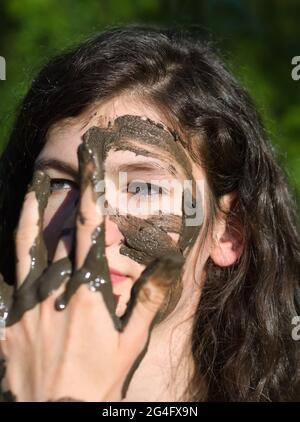 Visage boueux d'une jeune femme caucasienne à cheveux longs en plein air lors d'une Sunny Summer Day Banque D'Images