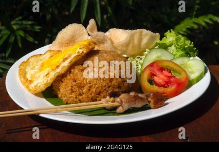 Nasi Goreng, riz frit, cuisine indonésienne traditionnelle, avec œuf de poulet et légumes sur une assiette blanche. Cuisine indonésienne. Banque D'Images
