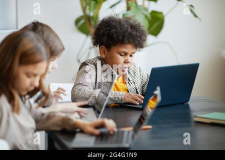 Divers groupes d'enfants utilisant des ordinateurs pendant la classe INFORMATIQUE à l'école Banque D'Images