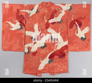 . Haori pour une femme avec un ornement sur tout le plan des oiseaux de grue blanche et rouge en vol, la doublure sur tout le plat avec des grues d'origami blanc. Soie rose avec une décoration tissée damassé de grues, extérieur et doublure avec décoration yuzen peinte et feuille d'or. Juste l'écusson de la famille (mon) d'un motif floral stylisé (Hanabishi). Banque D'Images