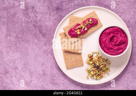 Végétarien, en-cas végétalien - houmous de betteraves, grains germés et chips de grains entiers. Banque D'Images