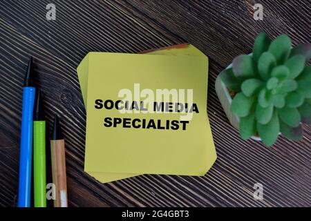 Le spécialiste des médias sociaux écrit sur des notes adhésives isolées sur une table en bois. Banque D'Images