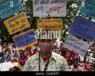 Kolhapur, Maharashtra, Inde. 21 juin 2021. Une travailleuse de la santé accréditée soulignant ses exigences avec des écriteaux décorés sur son épaule. Plus de 2000 travailleurs de l'ASHA ont protesté aujourd'hui au bureau du magistrat de district de Kolhapur pour leurs trois mois en attendant le salaire et d'autres demandes. Les travailleurs de la santé accrédités (ASHA) se battent en première ligne dans cette pandémie. CES vrais combattants du pied sont surchargés de tâches non-COVID et COVID. Ils risquent leur vie avec des engins de sécurité inadéquats et 33 INR comme incitatif COVID quotidien. Crédit : ZUMA Press, Inc./Alay Live News Banque D'Images