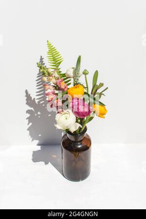 Bouquet d'été lumineux dans un vase ambre sur fond de marbre blanc. La vie éditoriale est encore sous un soleil éclatant. Banque D'Images