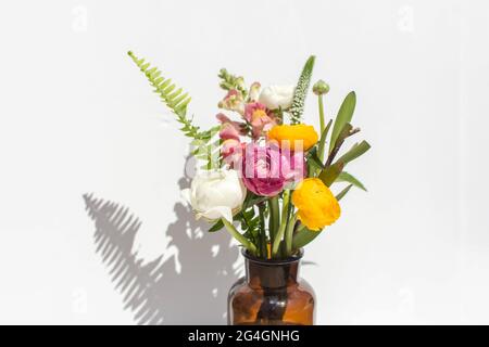 Bouquet d'été lumineux dans un vase ambre sur fond de marbre blanc. La vie éditoriale est encore sous un soleil éclatant. Banque D'Images