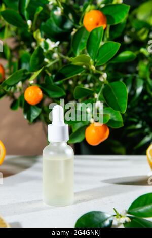 Huile essentielle d'agrumes naturelle. Bouteille d'huile essentielle naturelle sur fond de mandarine et d'arbre orange. Sérum de soin de la peau. Cosmétiques de vitamine C. Verticale Banque D'Images