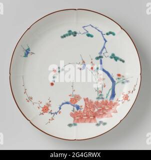 . Assiette en porcelaine à huit bords, peinte sur le glaçure en bleu, rouge, vert, jaune, noir et or avec les « trois amis de l'hiver » (bambou, prunus, pin) aux haies reliées. Sur le bambou un oiseau et aussi un dans l'air. Bord marron. Cinq préen dans la bague de pied. Ancienne étiquette sur le fond avec 'Collection Westendorp / 3'. Kakiemon. Banque D'Images