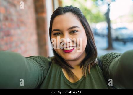 Jeune femme de taille plus prenant un selfie. Banque D'Images