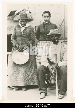 Carte postale noir et blanc avec une photo de Harriet Tubman, de son mari Nelson Davis et de leur fille adoptive Gertie. Harriet Tubman, activiste afro-américain de la lutte contre l'esclavage (c1820-1913), est née dans l'esclavage au Maryland. Elle s'est échappée en 1849, est devenue un Abolitionniste de premier plan et a été active comme 'chef d'orchestre' dans le chemin de fer souterrain, le réseau qui a aidé les esclaves échappés à atteindre la sécurité. Tubman se tient sur la gauche, tenant une casserole ronde. La carte postale a été envoyée à Mariline Wilkins à Philadelphie, en Pennsylvanie, de Sedalia gaines, en 1992. Banque D'Images