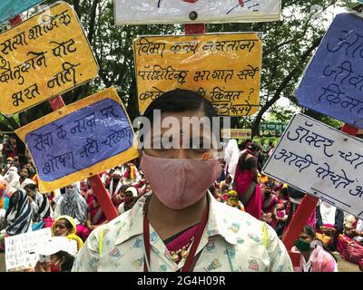 Kolhapur, Maharashtra, Inde. 21 juin 2021. Une travailleuse de la santé accréditée soulignant ses exigences avec des écriteaux décorés sur son épaule. Plus de 2000 travailleurs de l'ASHA ont protesté aujourd'hui au bureau du magistrat de district de Kolhapur pour leurs trois mois en attendant le salaire et d'autres demandes. Les travailleurs de la santé accrédités (ASHA) sont des travailleurs de première ligne dans cette pandémie. Ces personnes courageuses sont surchargées de tâches non COVID et COVID. Ils risquent leur vie avec des équipements de sécurité inadéquats et seulement 33 INR comme incitatif COVID quotidien. Les soixante-dix mille travailleurs de l'ASHA du Maharashtra sont sur l'indef Banque D'Images