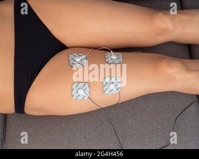 Femme en thérapie avec des électrodes placées sur les jambes, réadaptation post-traumatique Banque D'Images