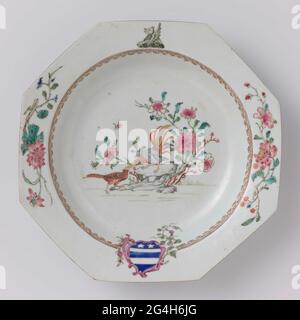 . Assiette à soupe octogonale en porcelaine, peinte sur le glaçage en bleu, rouge, rose, vert, jaune, noir et or. Sur le plat deux faisans avec une roche avec des plantes à fleurs; sur le mur une bordure en forme de tête de Spearhead interrompue par les bras de la famille des Vlovers entouré de branches de fleurs et de raisins. Sur le bord, en face de l'arme, le casque signe sous la forme d'un dragon. En outre, deux branches de fleurs (pivoine, lotus). Porcelaine arme avec couleurs email. Banque D'Images