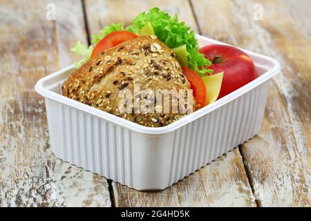 Boîte à lunch saine contenant un sandwich au fromage à grains entiers avec tomates, laitue et pomme rouge Banque D'Images