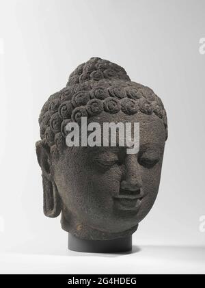 . Cette tête vient probablement d'une des 504 statues de Bouddha placées sur et autour du grand monument bouddhiste de Borobudur. Toutes ces figures représentent le Bouddha assis, avec ses yeux coulés. La tache relevée entre les sourcils, l'ourna, et la protubérance sur la tête, l'ushnisha, signifient la sainteté du Bouddha. Banque D'Images