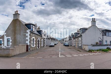 Vue le long de la rue bordée d'anciens chalets de pêcheurs à Portknokie, Moray, Écosse, Royaume-Uni Banque D'Images