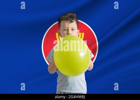 Journée des enfants dans l'Association des nations de l'Asie du Sud-est. Garçon blanc avec un ballon sur le fond du drapeau de l'Association de NAT d'Asie du Sud-est Banque D'Images