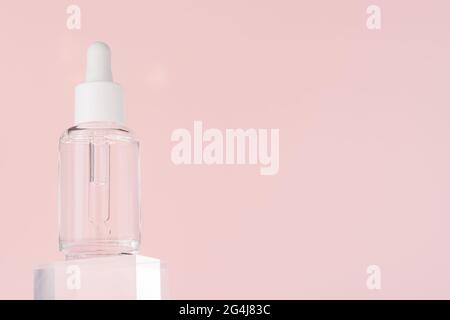 Huile d'acide hyaluronique, sérum avec collagène et peptides produit de soin de la peau sur cube acrylique transparent. Maquette de liquide cosmétique dans un flacon transparent Banque D'Images