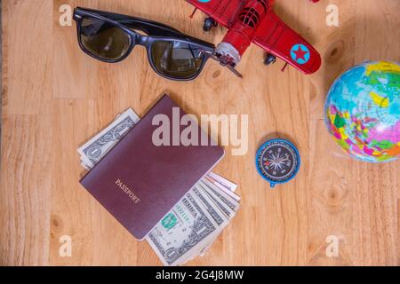 Concept de voyage, passeport, argent, boussole, avion, lunettes de soleil sur table en bois.Accessoires pour voyageurs, vue du dessus Banque D'Images